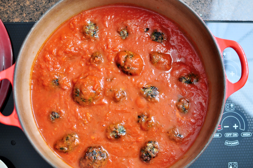 Spinach meatballs cooking in marinara sauce