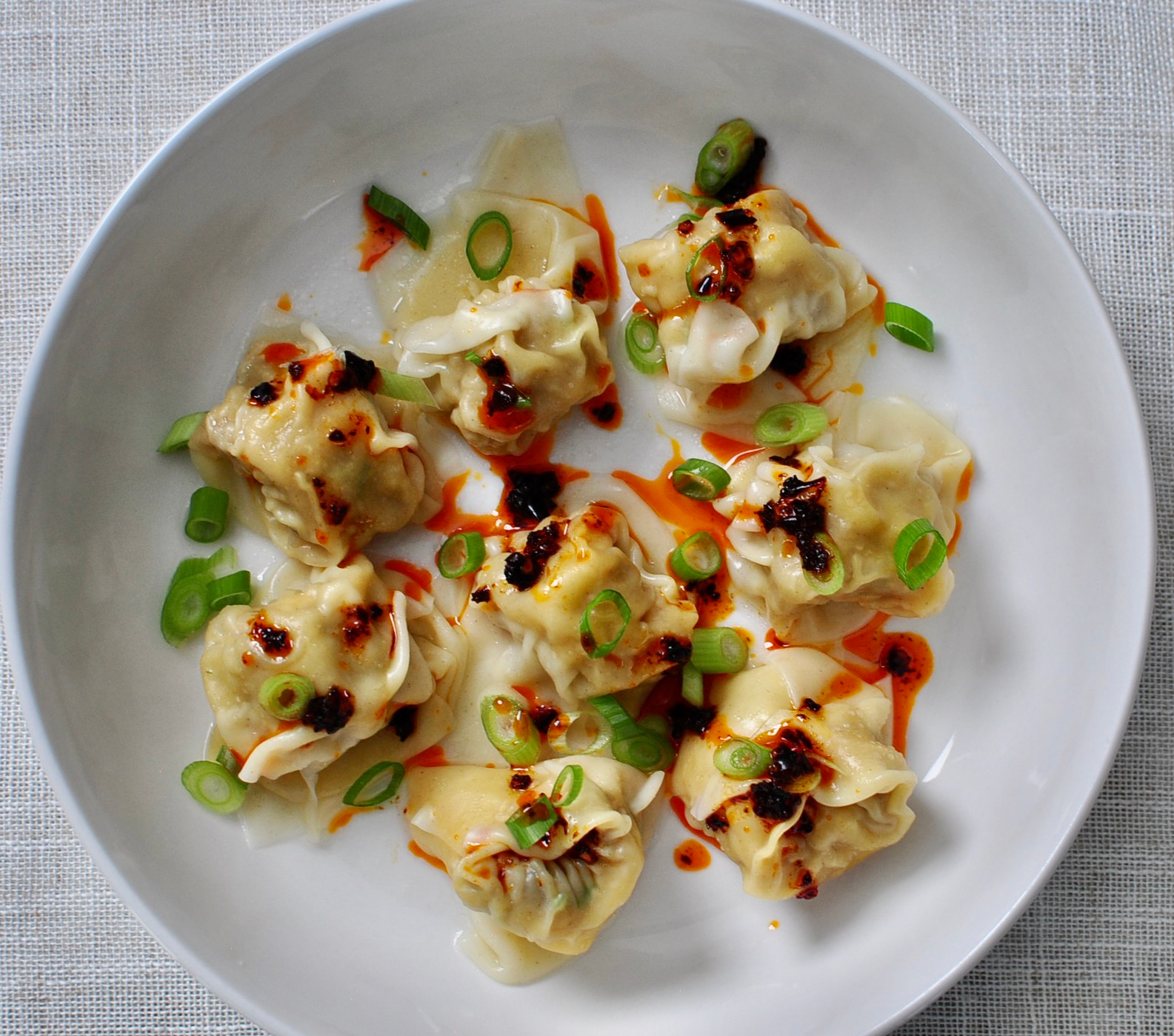 Wontons garnished wit scallions and chili crisp